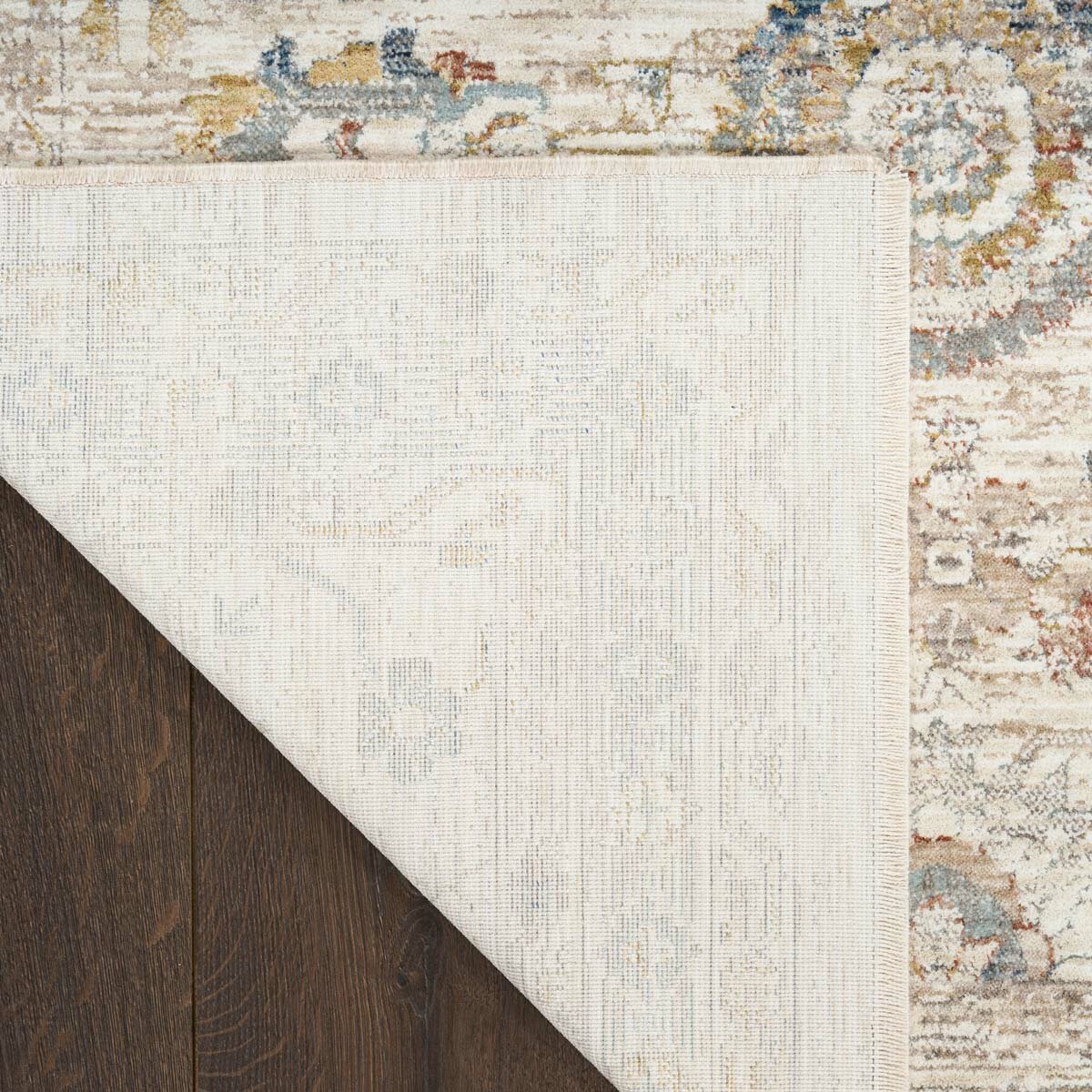 Beige rug with symmetrical floral and geometric pattern in muted blue, red, yellow, and grey