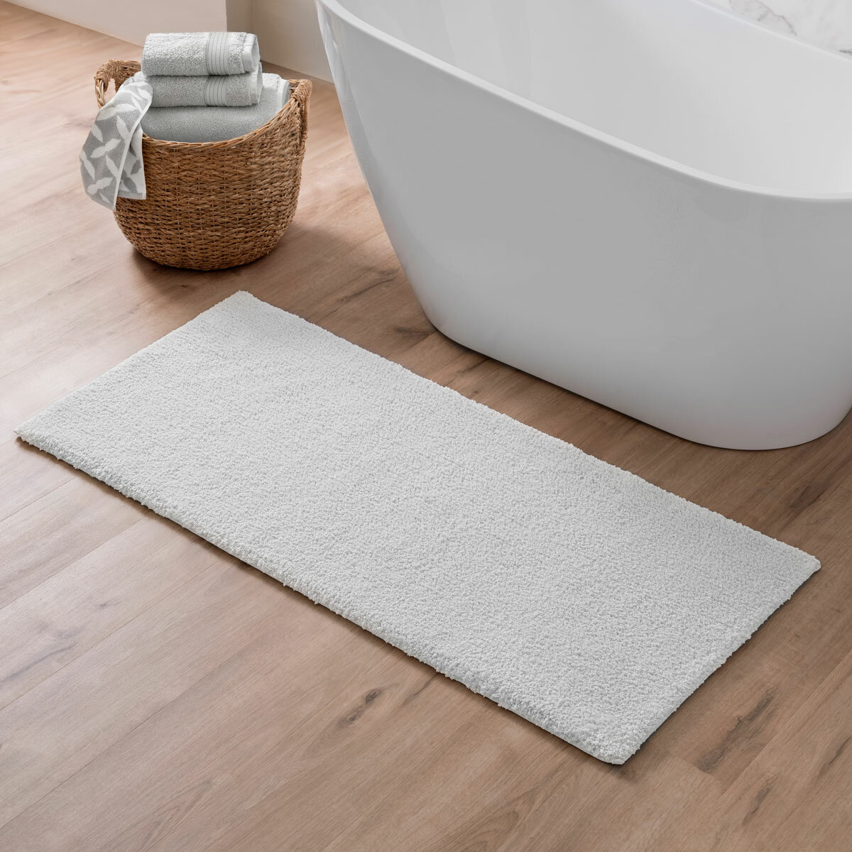 Freestanding tub with White bath mat laid at front of it