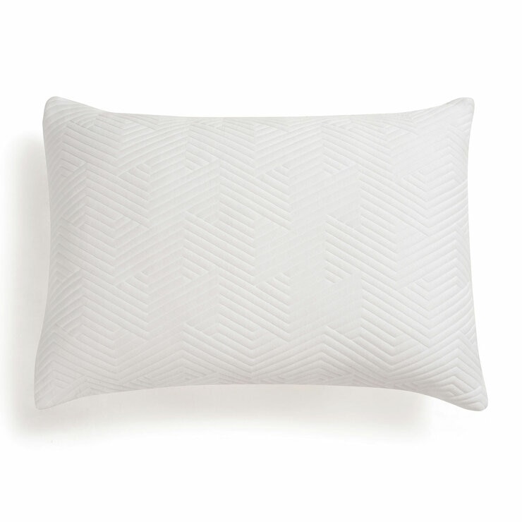 White pillow with a raised geometric zigzag pattern, shown on a bed