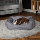 Lifestyle image of dog sitting on pet bed in living room setting