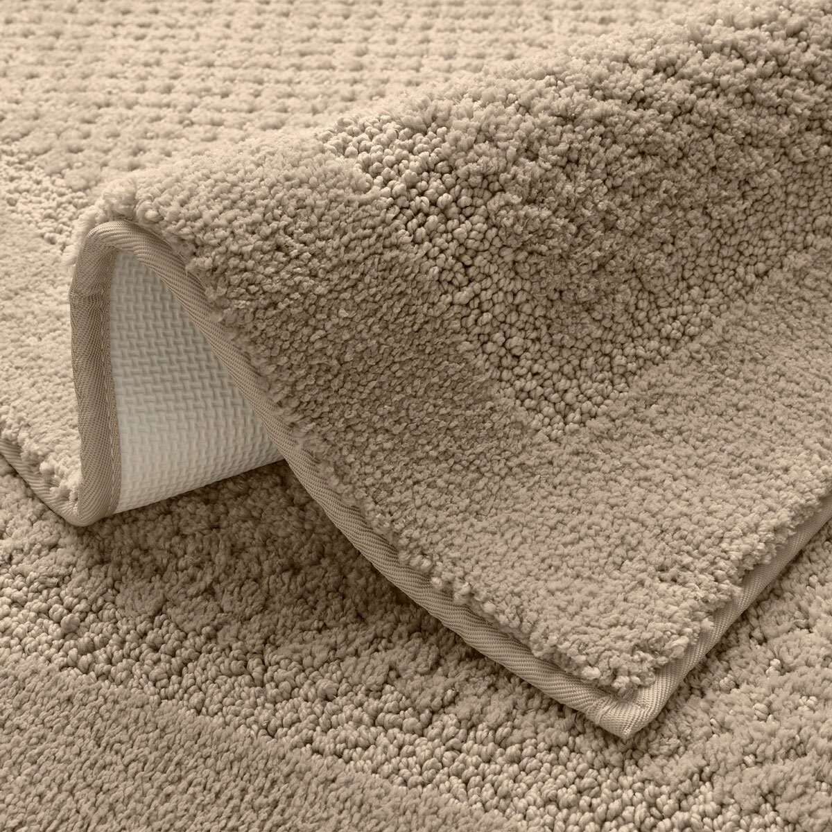 Beige bath mat with a textured surface and non‑slip backing Beige bath mat with a textured surface and non‑slip backing