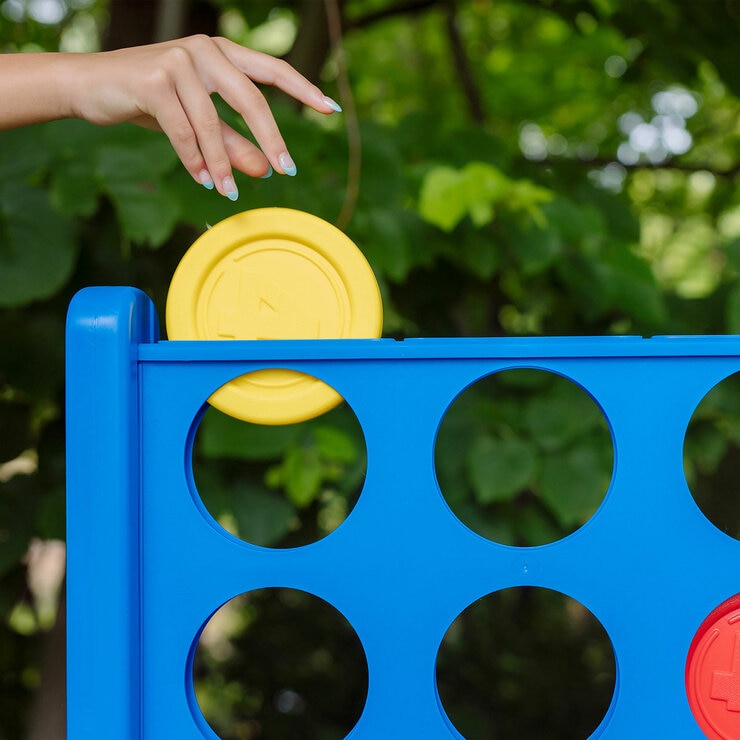 Lifestyle image of a game piece being dropped into the Giant Connect 4 grid