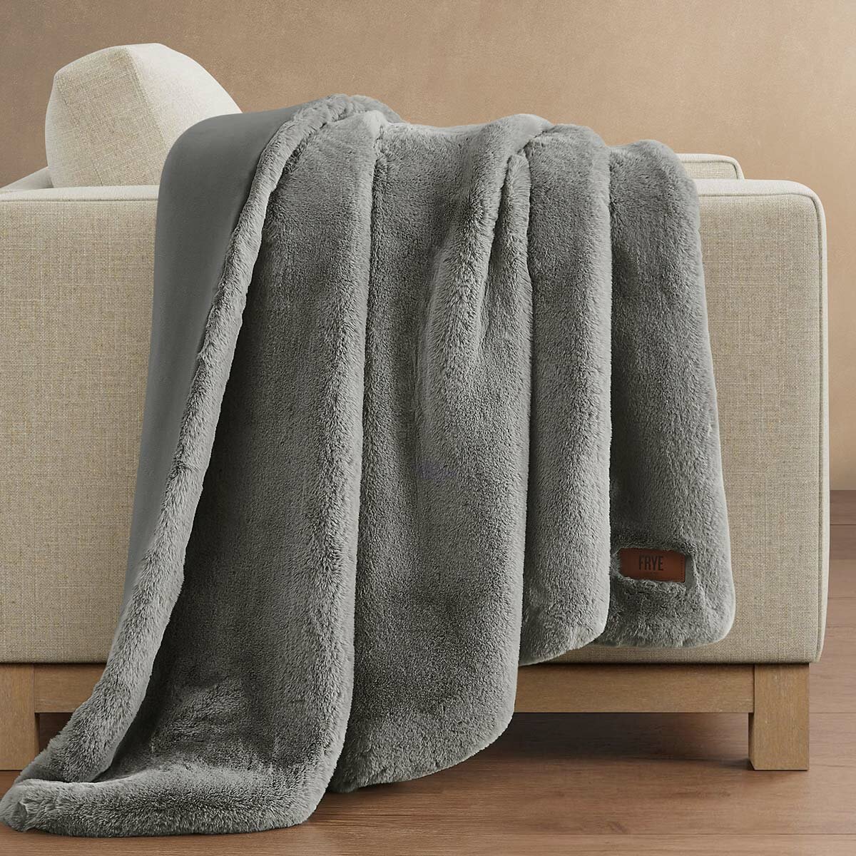 Soft grey faux fur throw resting on the arm of a beige sofa