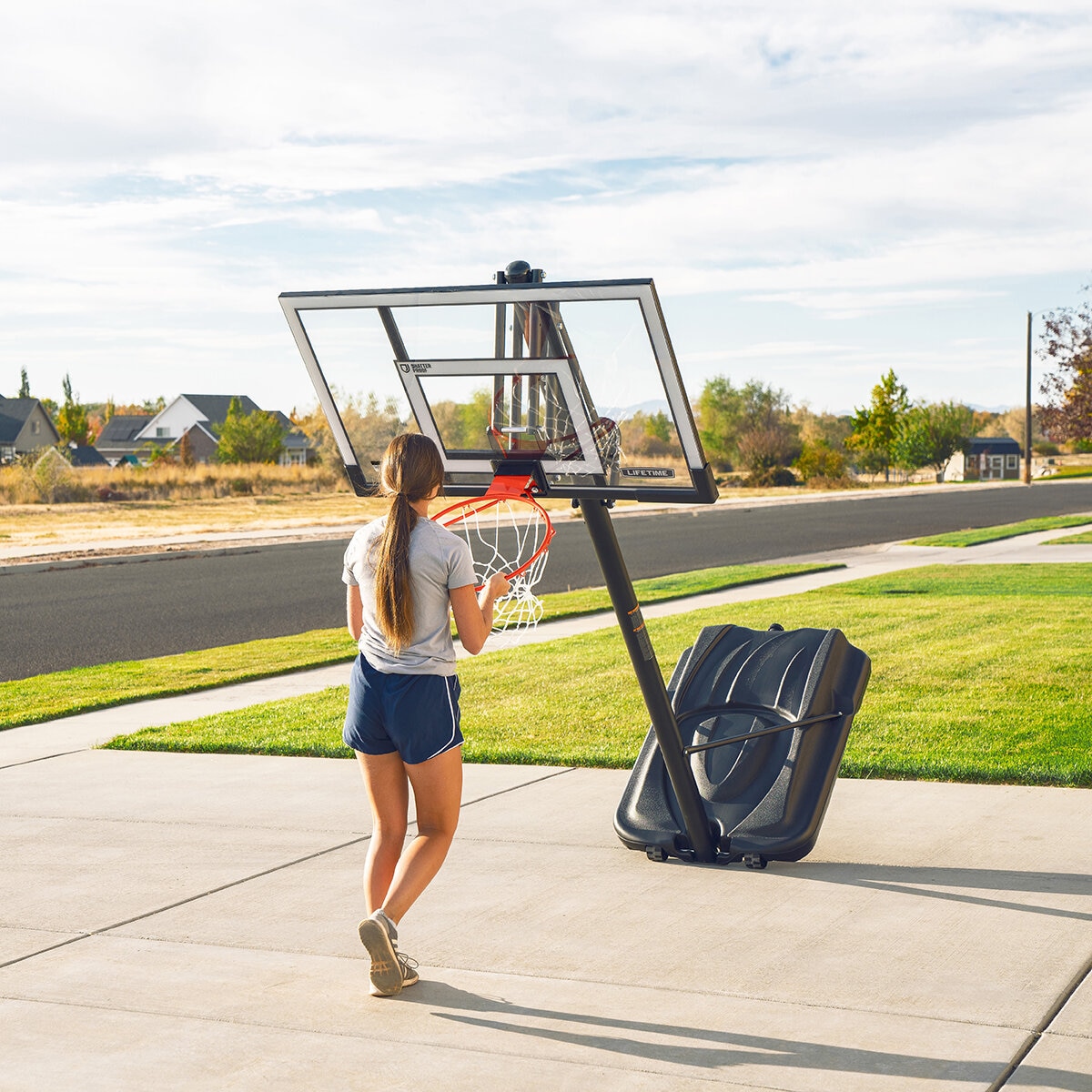 Lifestyle image shoiwng a woman moving the basketball hoop Lifestyle image shoiwng a woman moving the basketball hoop