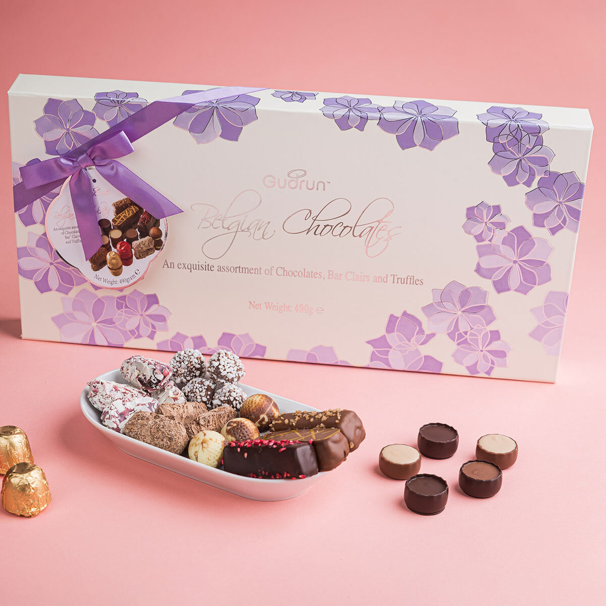 Clifestyle image of chocolate box on pink background