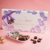 Lifestyle image of chocolate box on pink background
