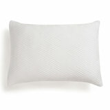 White pillow with a raised geometric zigzag pattern, shown on a bed