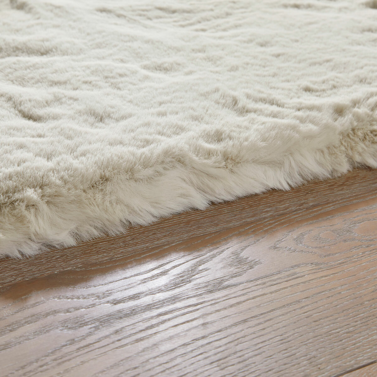 Cream faux fur rug with thick, fluffy texture on wooden floor