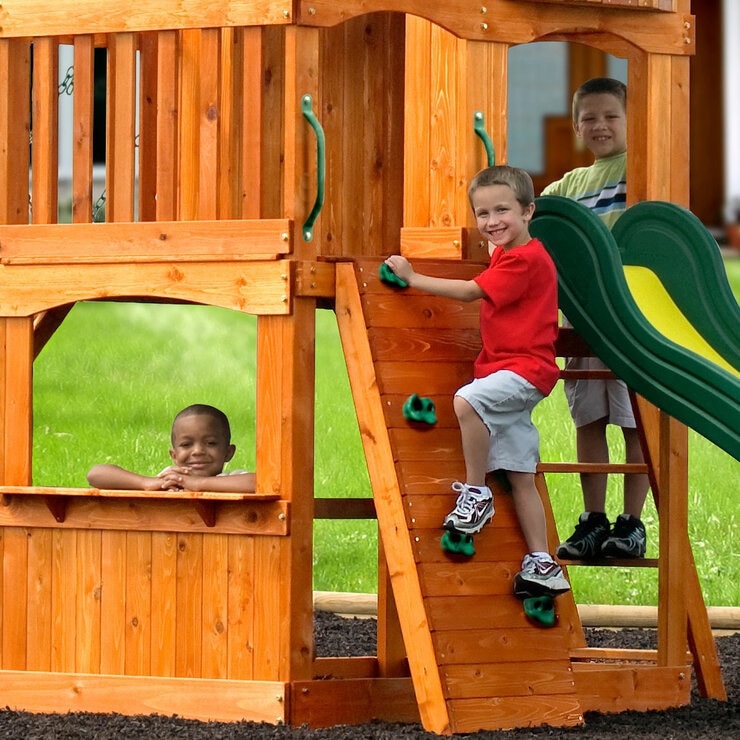 Lifestyle image of a child climbing the ladder, another climbing the rock wall, and another looking out from the bottom of the playcentre