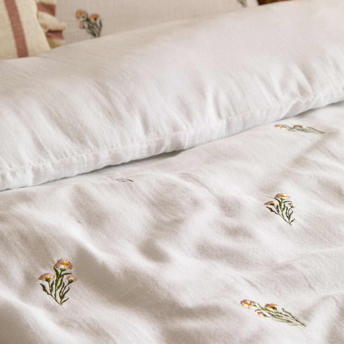 Soft white duvet set with a subtle scattered floral pattern, neatly laid across a made bed