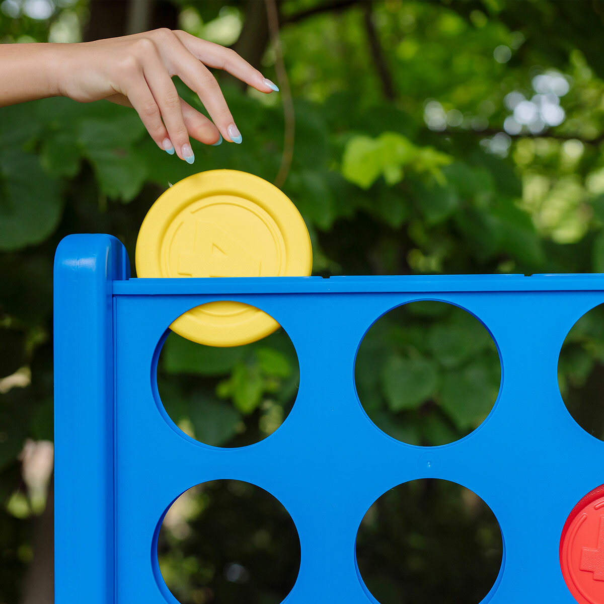 Lifestyle image of a game piece being dropped into the Giant Connect 4 grid