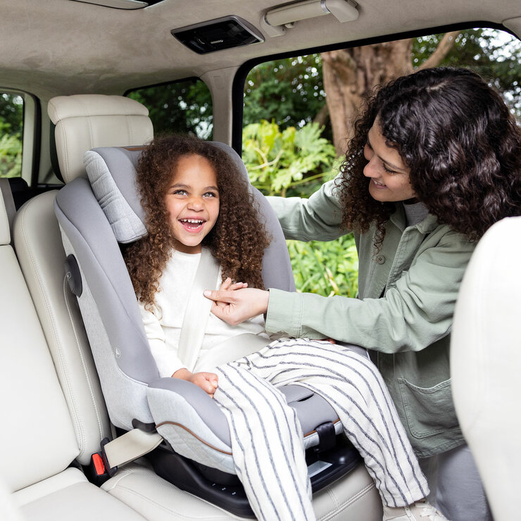 Lifestyle image of a woman buckling a child into the seat