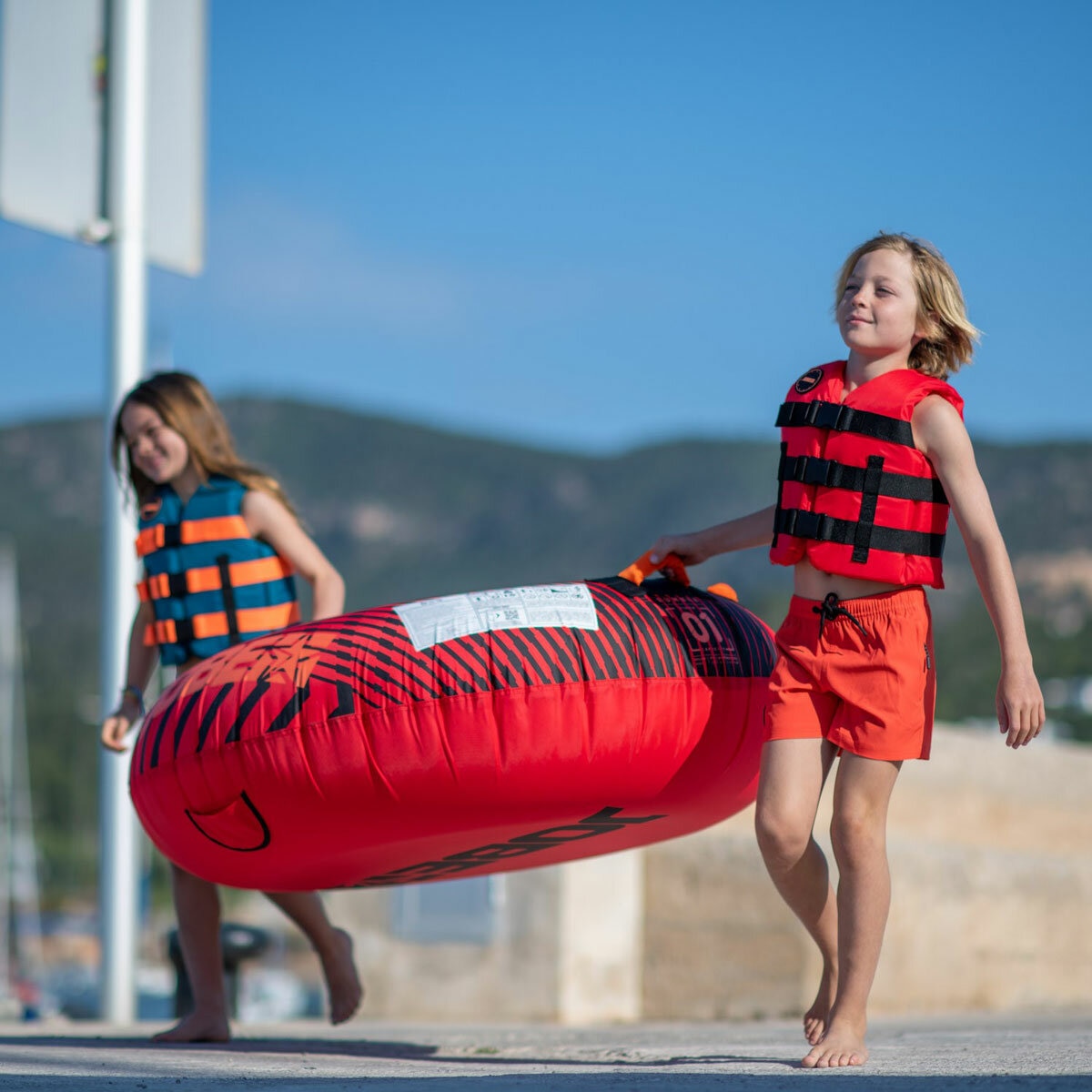 Lifestyle image of two children carrying the towable Lifestyle image of two children carrying the towable