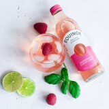 Bottle with Glass containing drink with Raspberry and Ice in on a Table