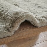 taupe faux fur rug with thick, fluffy texture on wooden floor taupe faux fur rug with thick, fluffy texture on wooden floor
