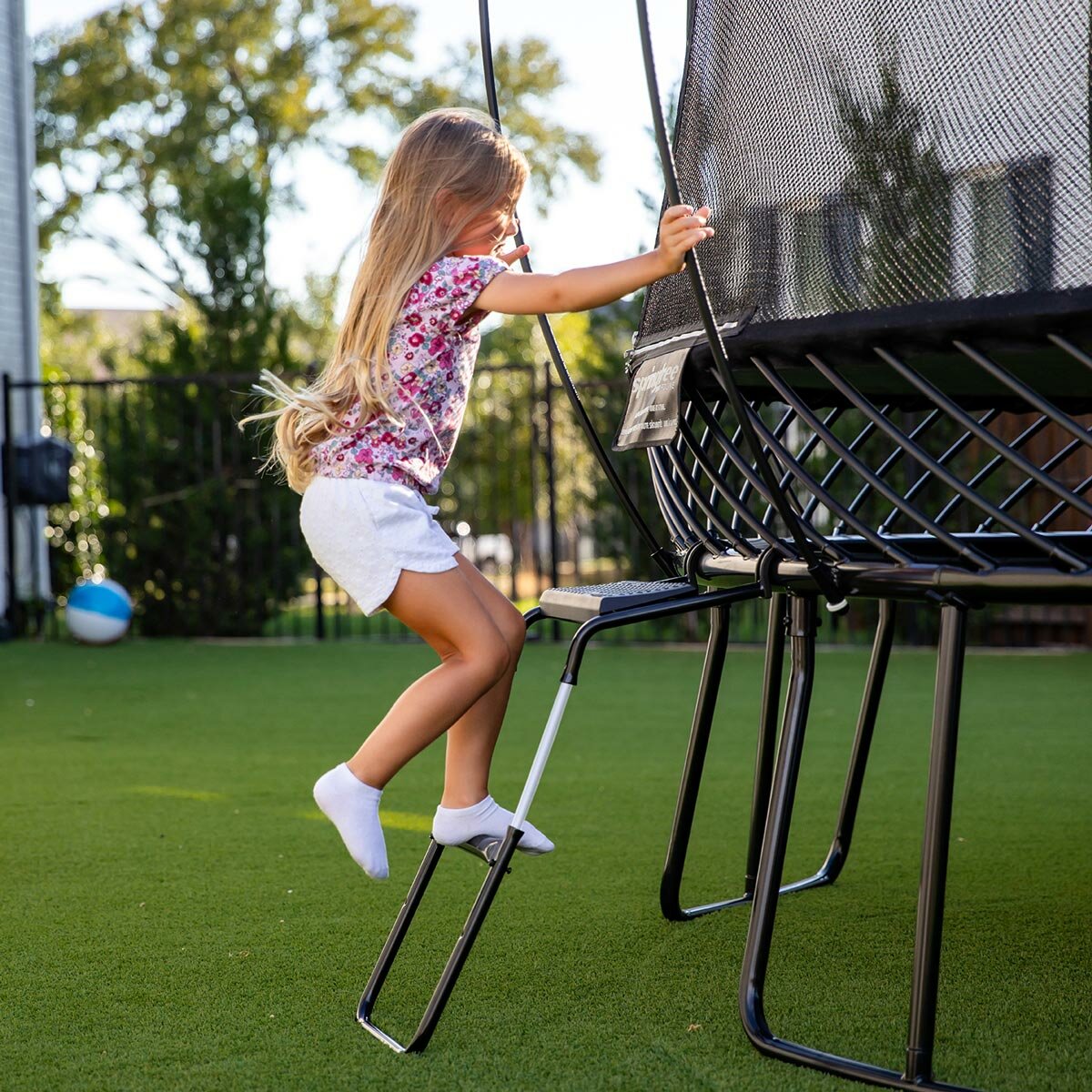 A lifestyle image of a girl climbing a ladder into the Springfree Trampoline