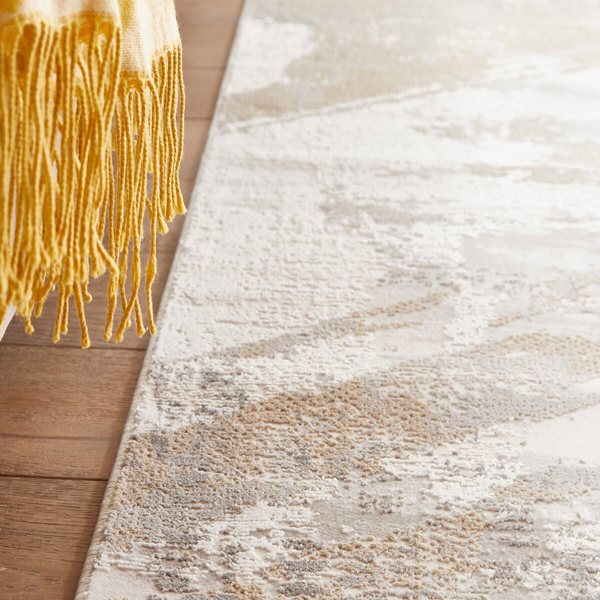 Close-up of a plush abstract rug in beige, grey and white with raised, distressed-style texture.