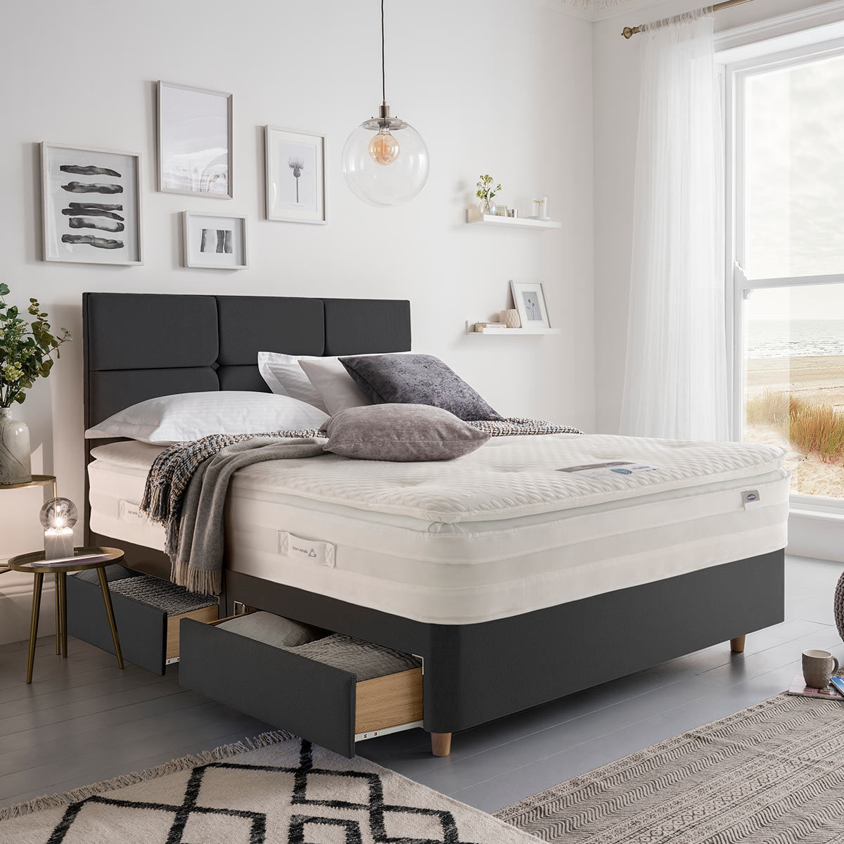 Lifestyle image of made up bed in ebony in front of window showing beachside