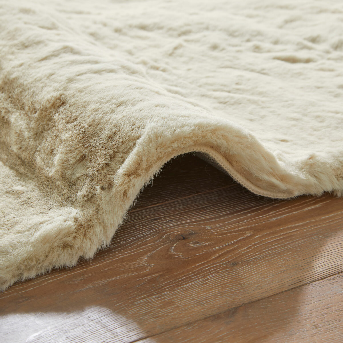 beige faux fur rug with thick, fluffy texture on wooden floor