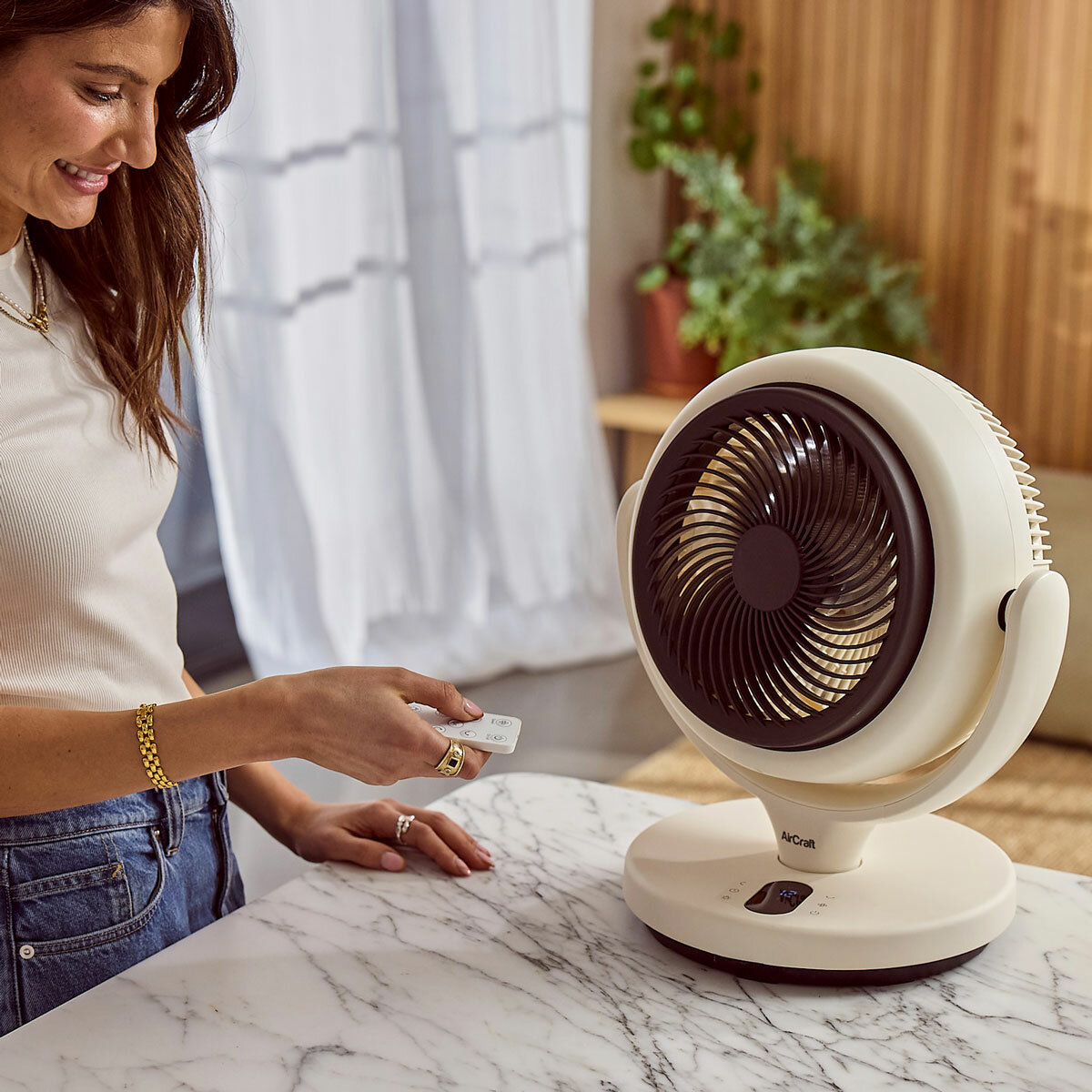 Lifestyle image of AirCraft Lume Mini Air Circulator being used in the kitchen with a remote Lifestyle image of AirCraft Lume Mini Air Circulator being used in the kitchen with a remote