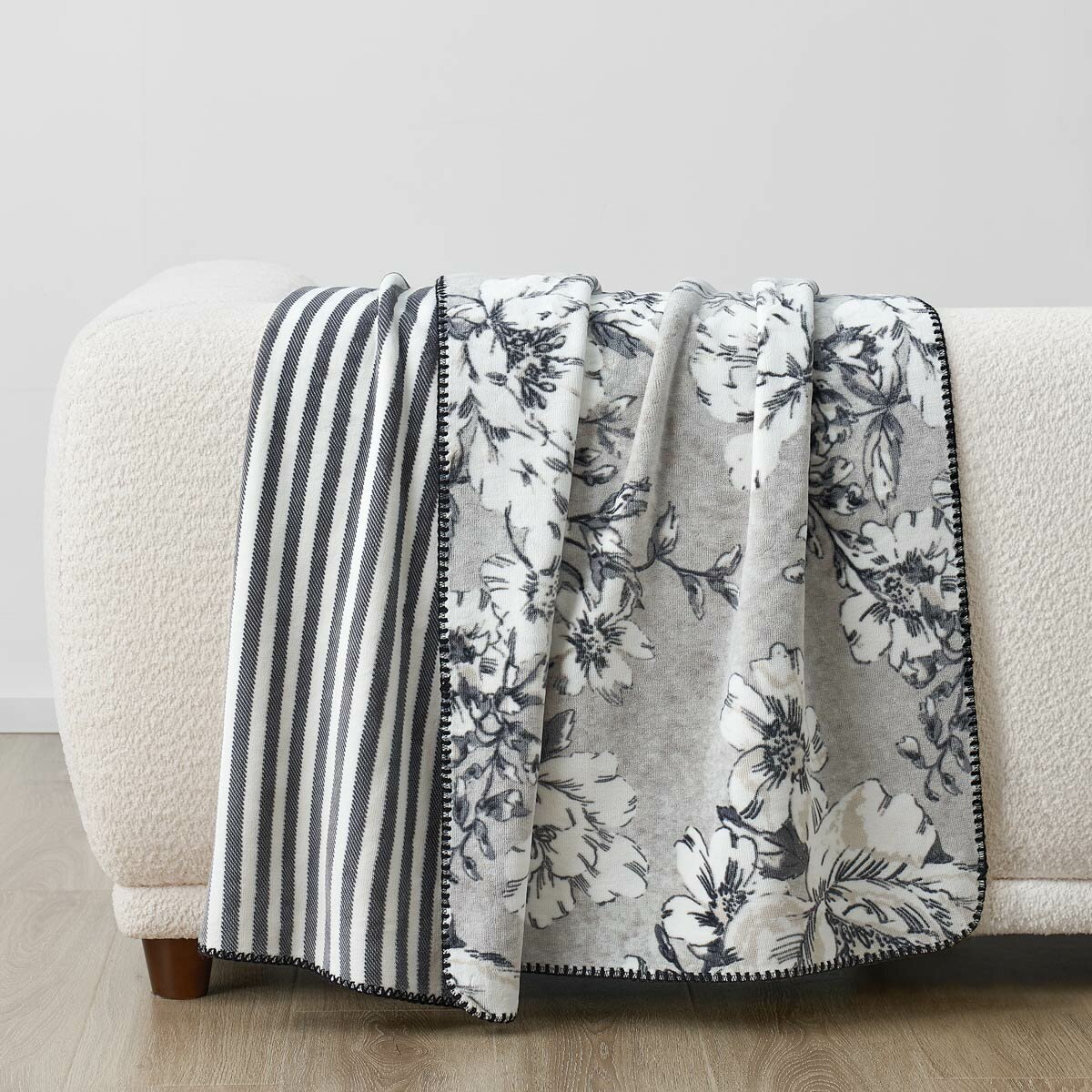 Black and white floral throw staged on white sofa in a lifestyle image Black and white floral throw staged on white sofa in a lifestyle image