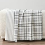 Grey floral throw staged on white sofa in a lifestyle image