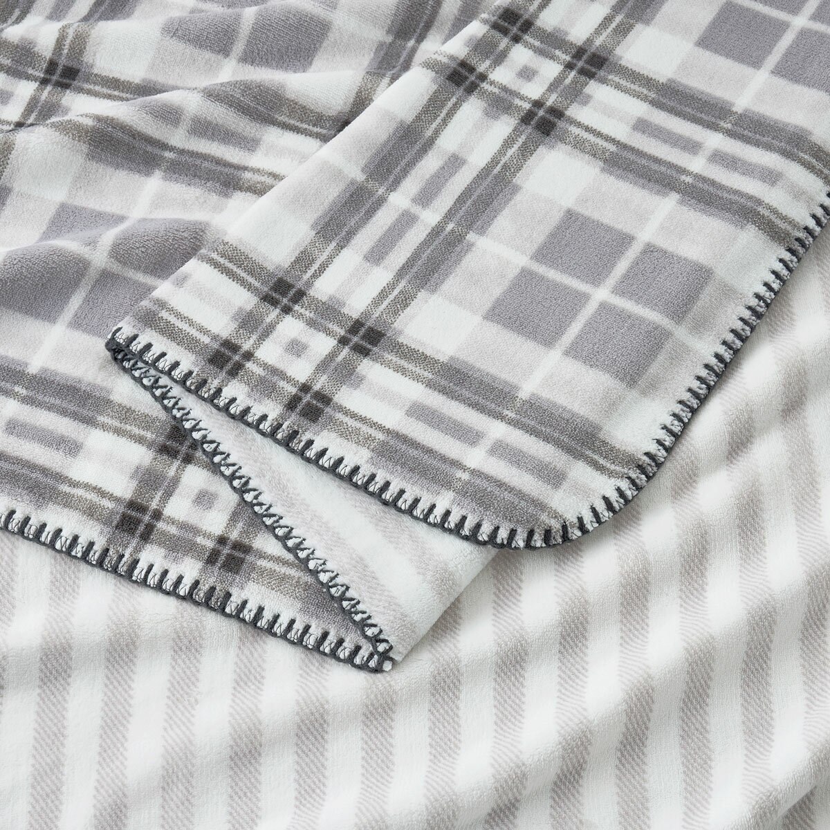 Grey floral throw zoomed in, soft plush look with outer edge thread trimming