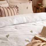 Soft white duvet set with a subtle scattered floral pattern, neatly laid across a made bed