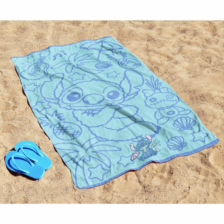 Blue Stitch character beach towel laid out on sand