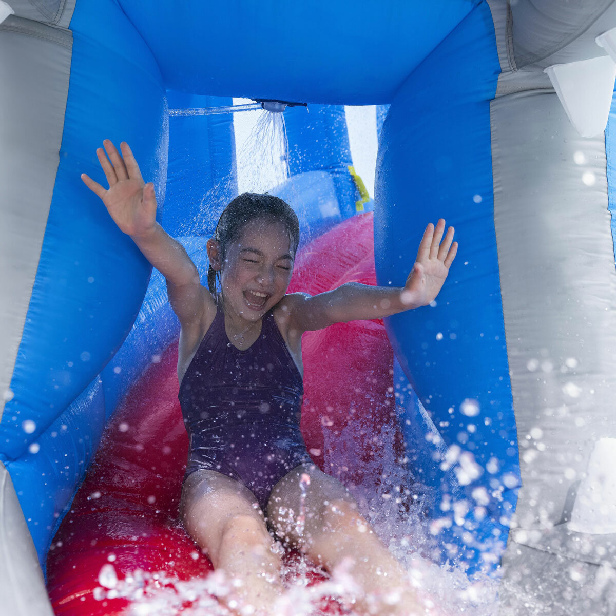Lifestyle image of a child sliding out the mouth of the whale as water sprays on them