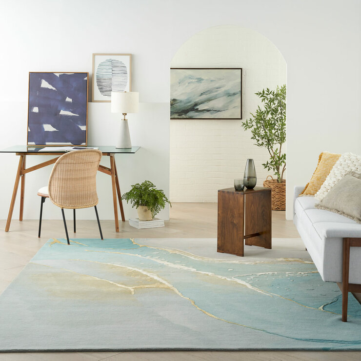 Large area rug with a coastal-style pattern in blue, beige and white, laid across light wood flooring in a modern home office and lounge space Large area rug with a coastal-style pattern in blue, beige and white, laid across light wood flooring in a modern home office and lounge space