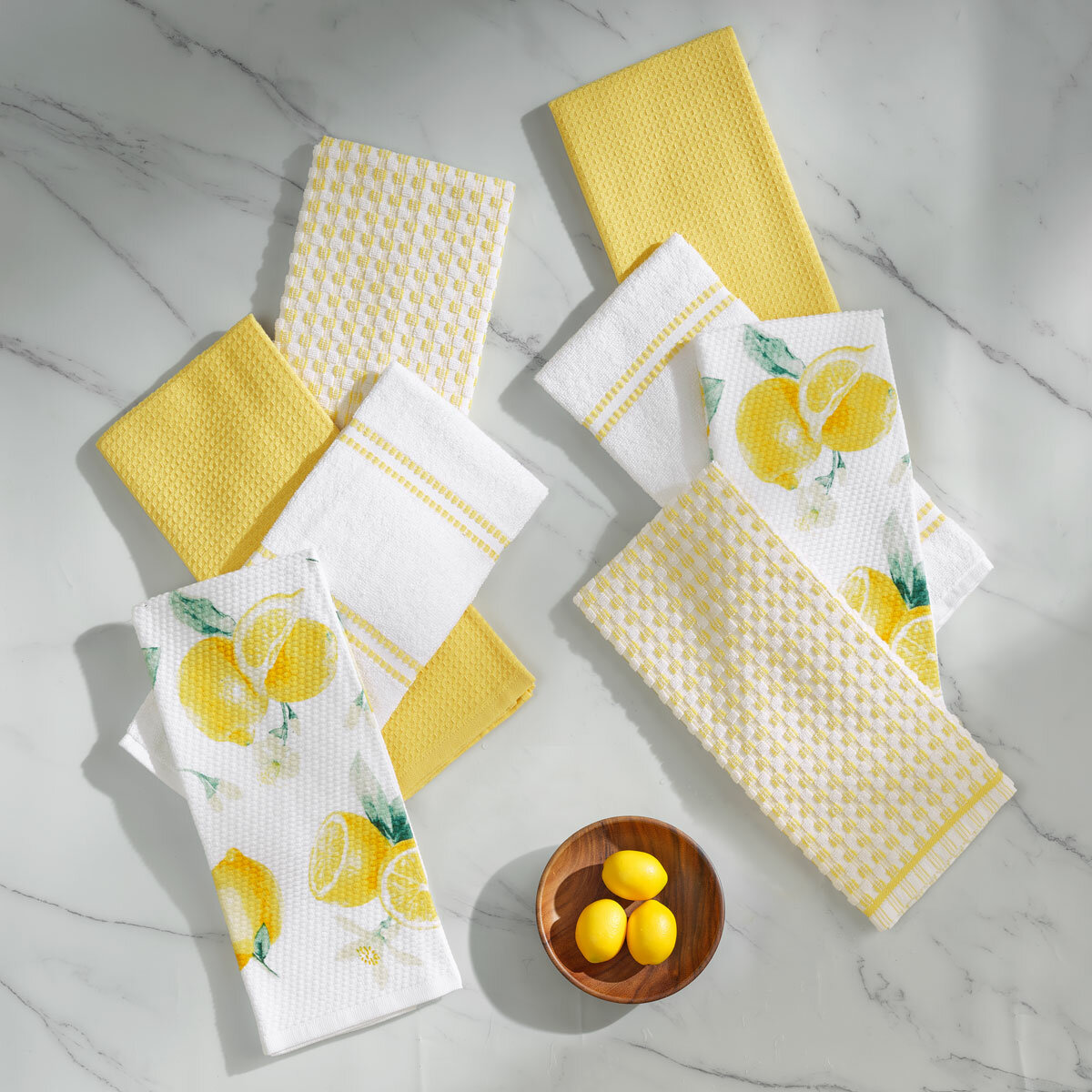 Eight yellow-themed tea towels arranged on a white marble surface, including designs with lemon prints, stripes, solids, and houndstooth patterns Eight yellow-themed tea towels arranged on a white marble surface, including designs with lemon prints, stripes, solids, and houndstooth patterns