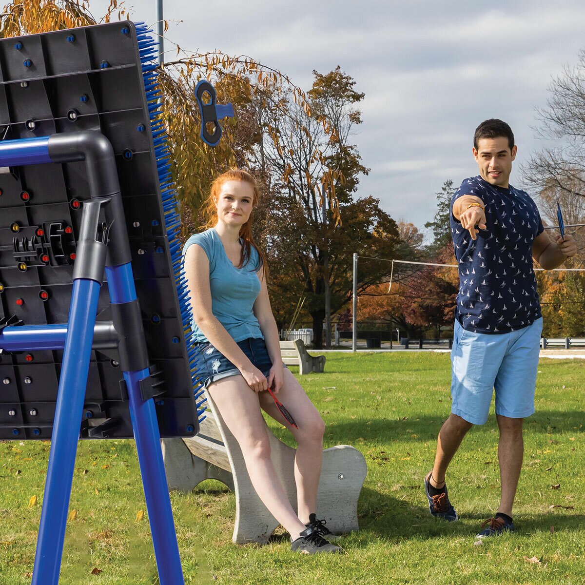 Lifestyle image of a man throwing an axe at the board while a woman watches Lifestyle image of a man throwing an axe at the board while a woman watches