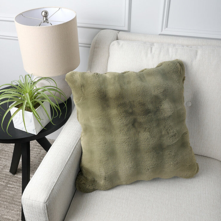 Green square cushion on a beige sofa, with a bubble texture