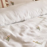 Soft white duvet set with a subtle scattered floral pattern, neatly laid across a made bed