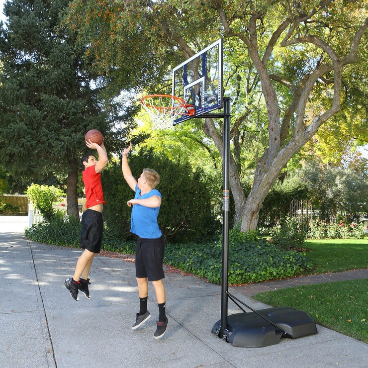Lifestyle image of two children playing basketball, one of which is shooting the ball into the hoop