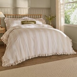 Beige and white striped duvet set with ruffled edges and matching pillow shams.