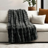 Dark grey textured throw laid across the arm and seat of a beige sectional sofa