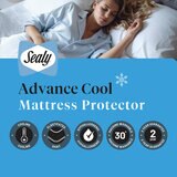 A fitted white mattress protector with a hexagonal quilted pattern on a neatly made bed in a modern bedroom