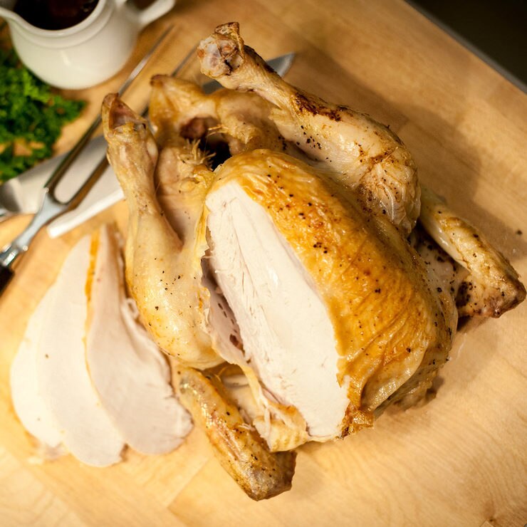 Cooked turkey with a slice cut out on a wooden chopping board Cooked turkey with a slice cut out on a wooden chopping board
