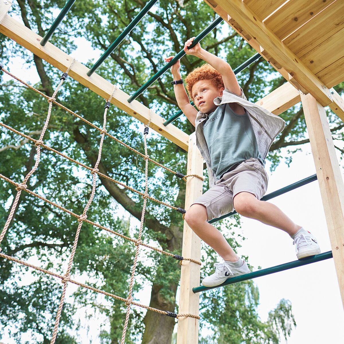 Lifestyle image of a child using the monkey bars Lifestyle image of a child using the monkey bars