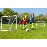 Lifestyle image of children paying football between the two goals, wearing the included bibs