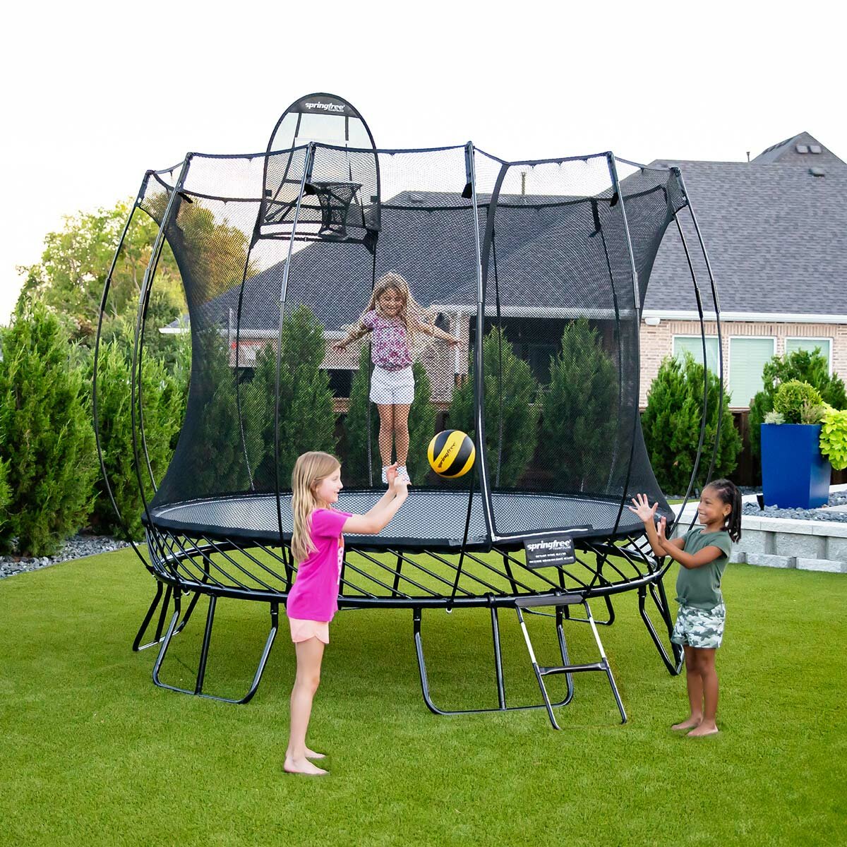 A lifestyle image of children playing on the Springfree 10ft Round Jumbo Trampoline