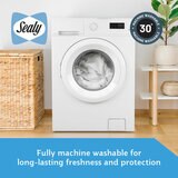 A fitted white mattress protector with a hexagonal quilted pattern on a neatly made bed in a modern bedroom