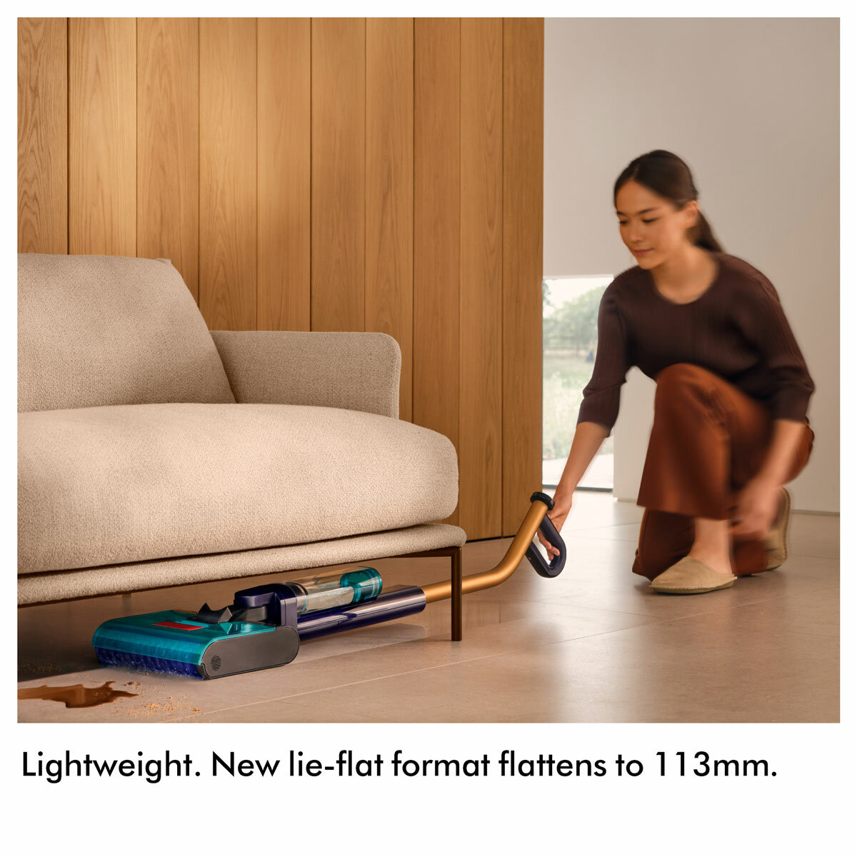 Lifestyle image of Dyson Clean+Wash Hygiene hard floor cleaner being used under the sofa