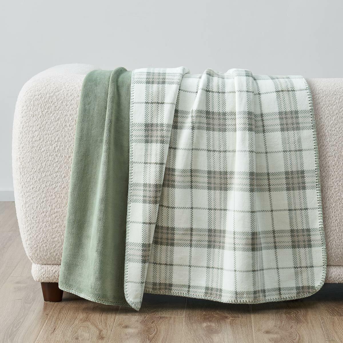 Sage green plaid throw staged on white sofa in a lifestyle image Sage green plaid throw staged on white sofa in a lifestyle image