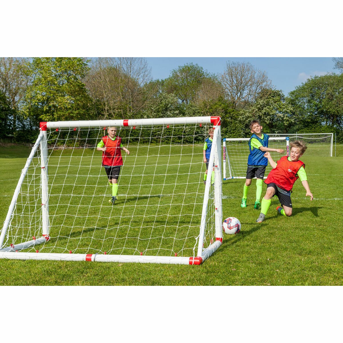 Lifestyle image of children playing football, one of them is scoring a goal