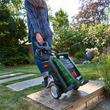 Women  walking up her garden wheeling her  Bosch Pressure Washer