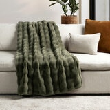 Olive green textured throw draped over a beige sofa with neutral cushions
