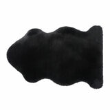 Black lambskin-style rug with an irregular, cloud-like shape and soft, fluffy texture on a light wooden floor